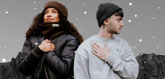 A man in a Hachure wool beanie and grey sweatshirt and woman in a Hachure snood and ear warmer looking cosy for winter