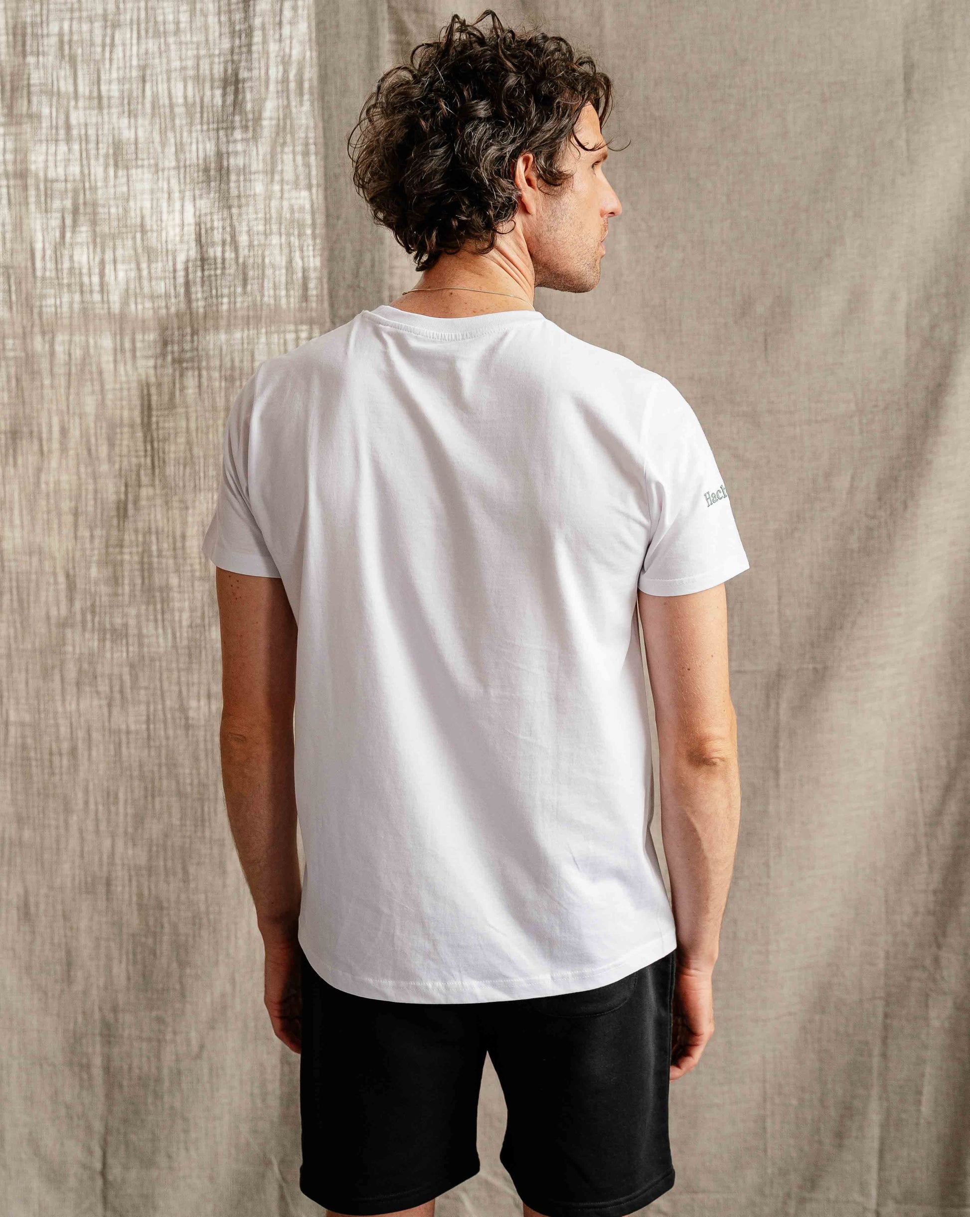 Man wearing Hachure Active white t-shirt with green logo embroidery 