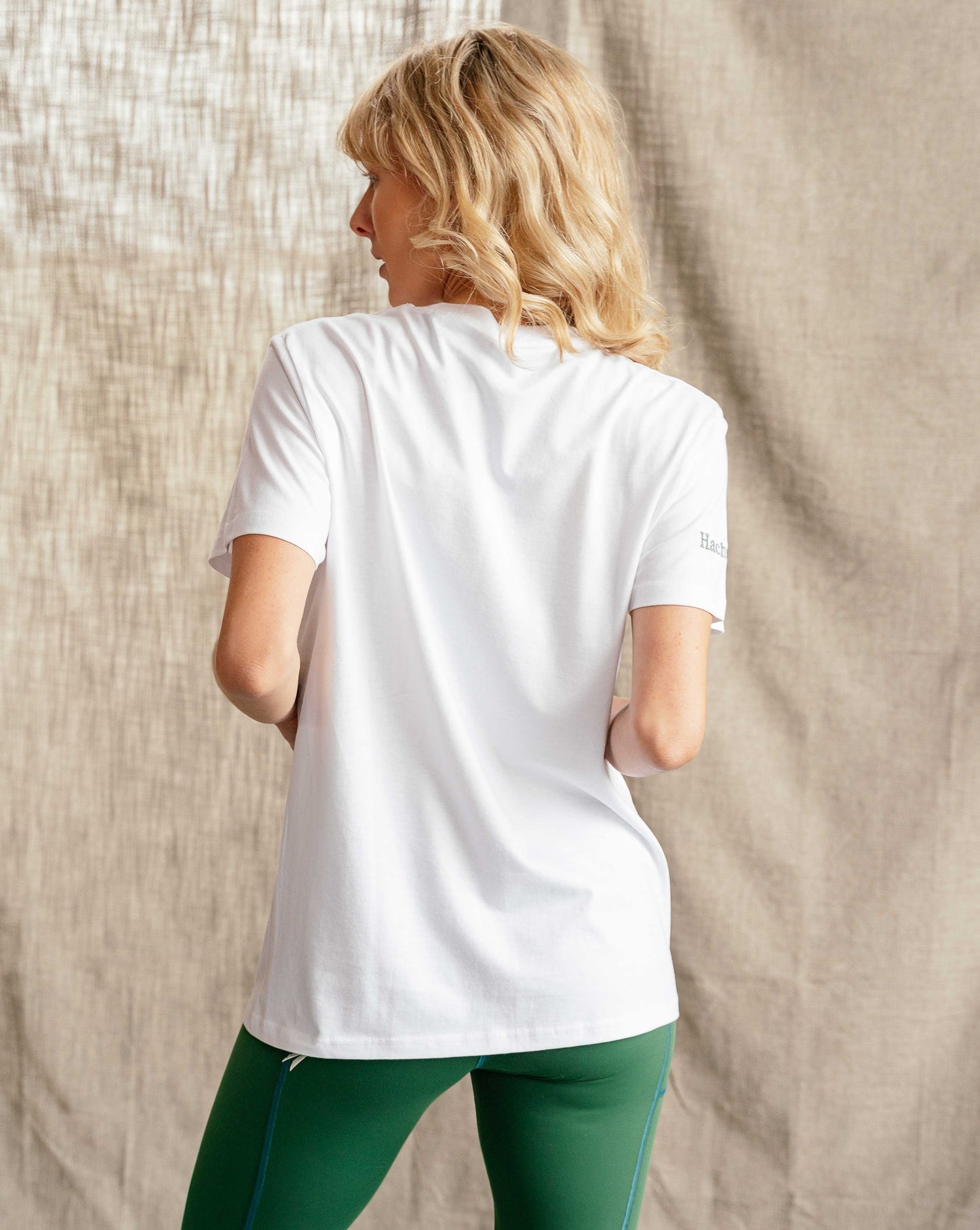 Woman wearing Hachure Active white t-shirt with green logo embroidery 