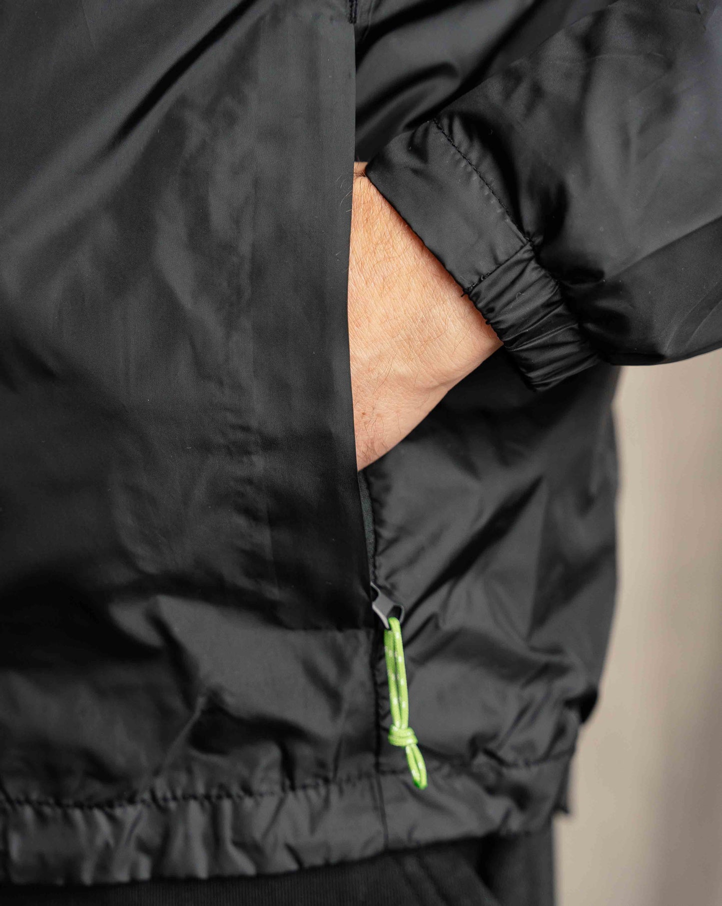 Man wearing Hachure Mountains full zip windbreaker in black zip pocket close up